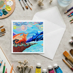 Colourful card with a dragon and mountains design on a table with art supplies