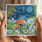 Colourful artwork of a kingfisher held by hands against a neutral background