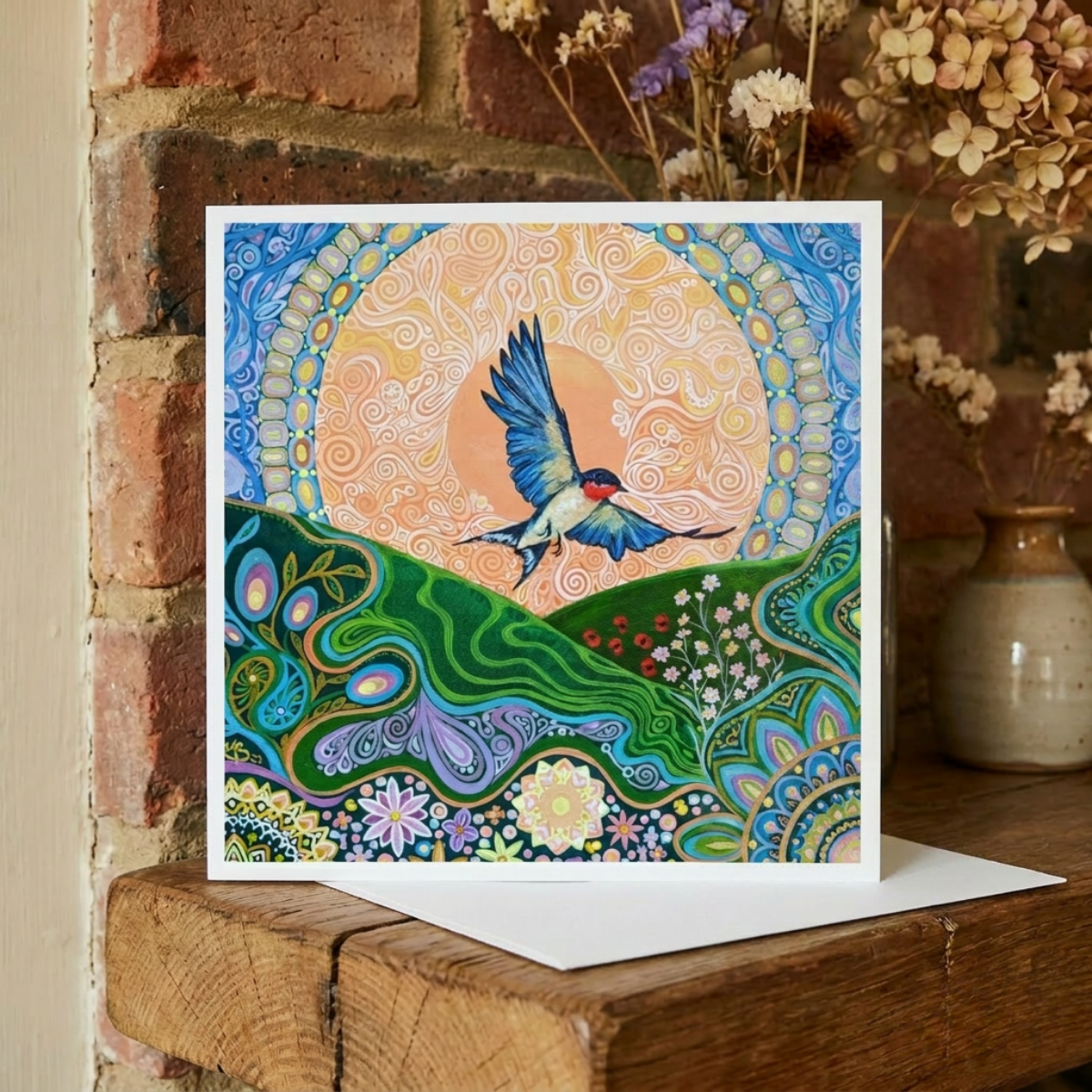 Colourful greeting card with a swallow bird design on a wooden surface with a brick wall background.