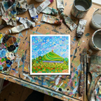 Colourful abstract painting on a messy artist's table with paint tubes and brushes.