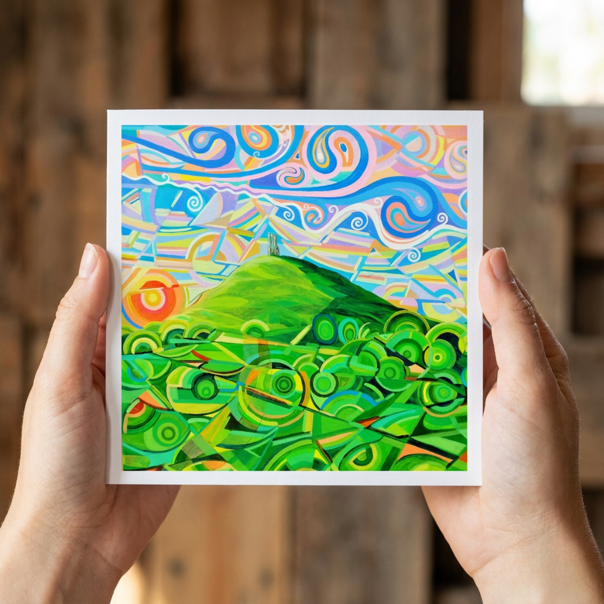 Colourful abstract artwork held by hands against a wooden background