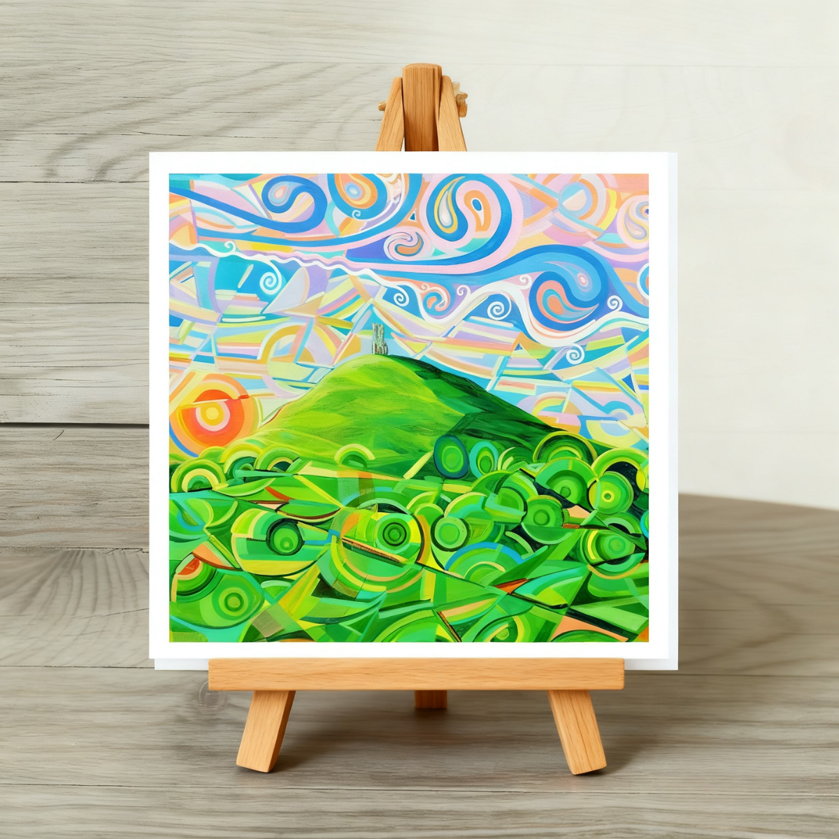 Colourful abstract landscape painting of Glastonbury Tor on a wooden easel against a neutral background