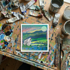 Artistic depiction of a wolf in a scenic landscape on a paint-splattered table with art supplies.