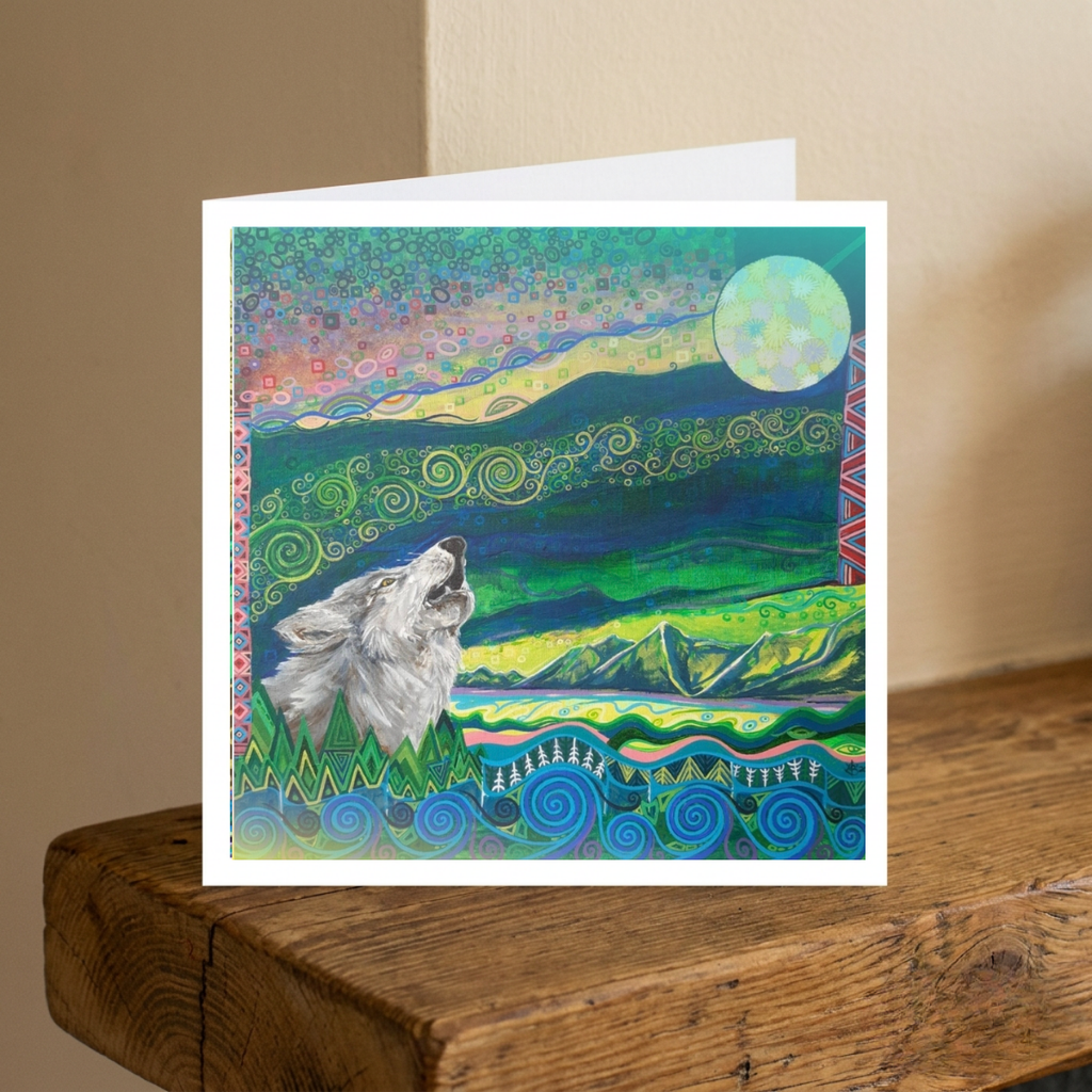 Greeting card with a wolf howling at the moon design on a wooden surface.