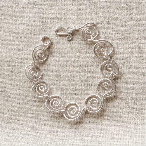 Silver spiral bracelet on a fabric surface