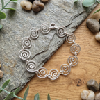 Alice Silver Spiral Bracelet on a wood and slat surface