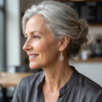 Woman with grey hair smiling in a casual setting wearing a pair of Alice spiral earrings