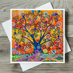 Colourful tree of life design on a card with a white envelope on a wooden surface