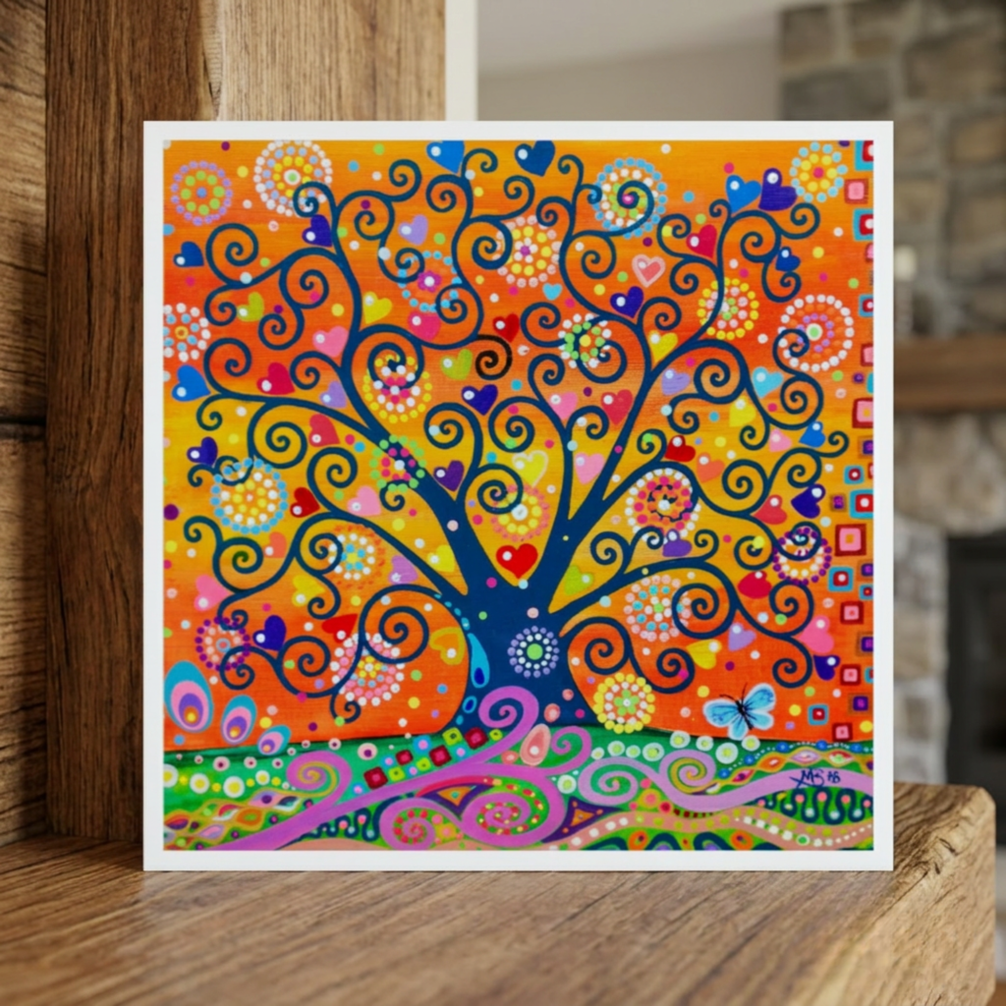 Colourful abstract tree artwork greeting card on a wooden surface with a blurred background