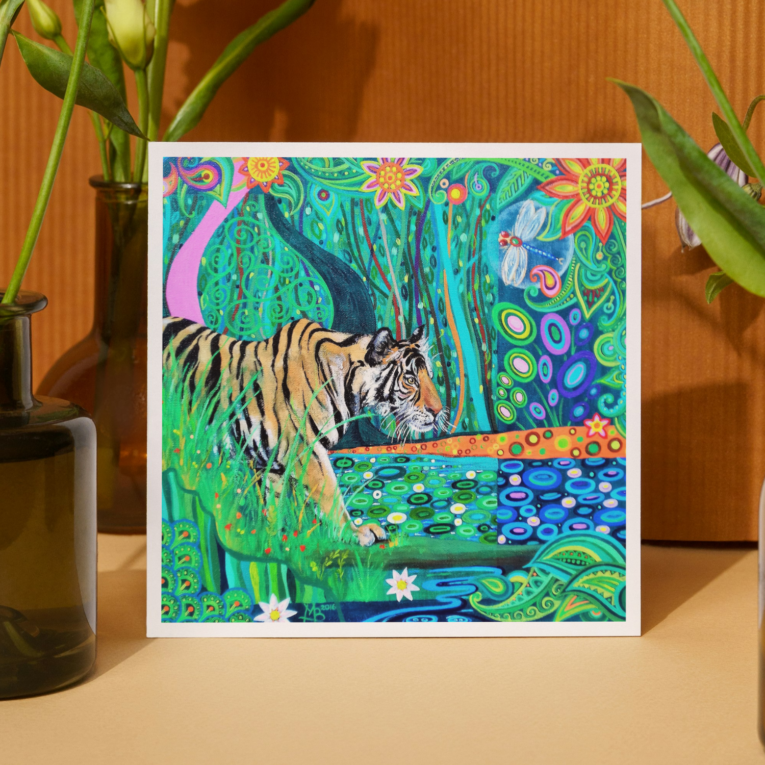 Colorful artwork of a tiger in a natural setting with plants on a wooden surface.