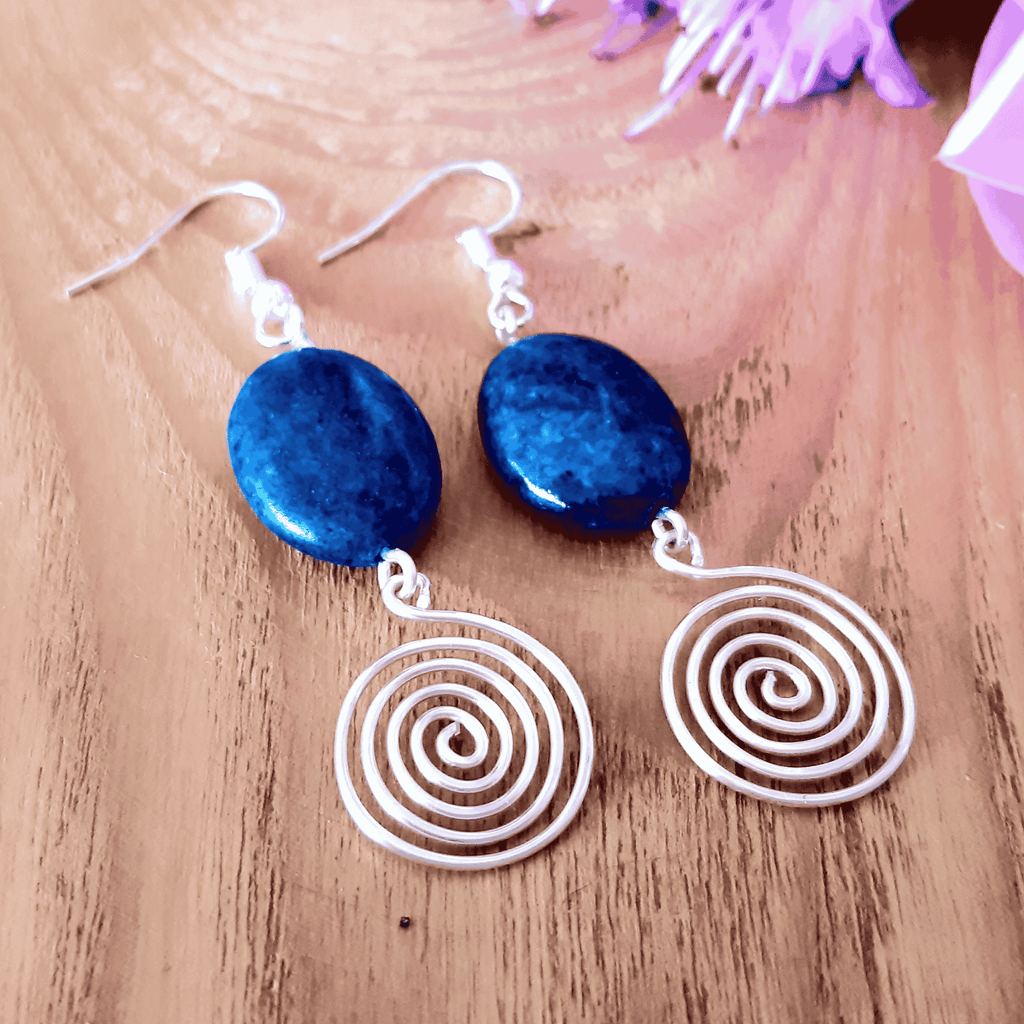 Blue stone earrings with spiral designs on a wooden surface
