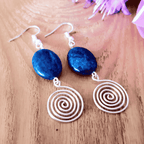 Blue stone earrings with spiral designs on a wooden surface