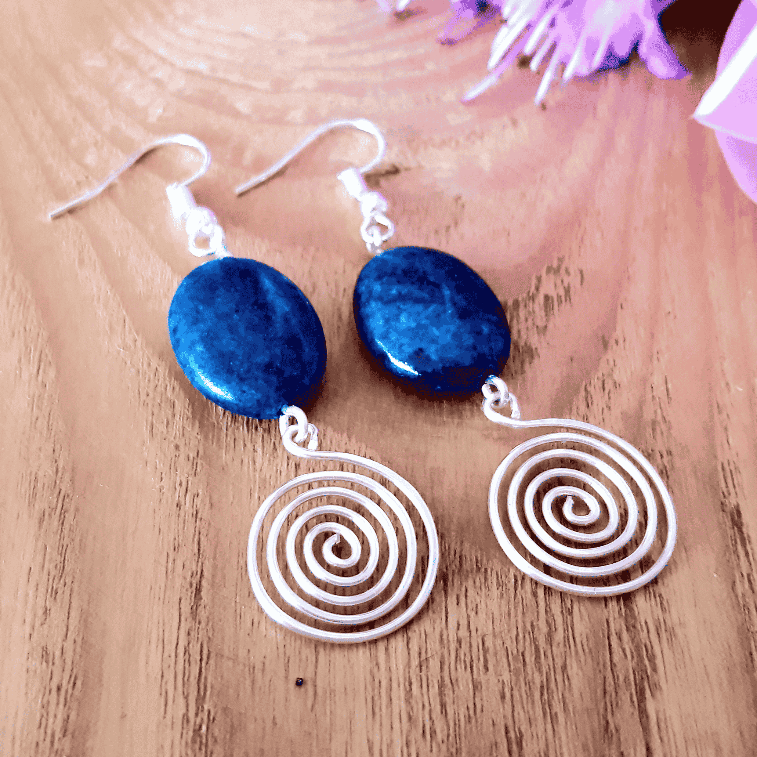 Blue stone earrings with spiral designs on a wooden surface