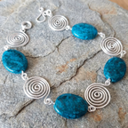 Bracelet with blue stones and silver spiral designs on a stone surface