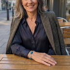 Woman sitting at an outdoor table, smiling wearing a Azurite and silver spiral bracelet