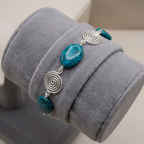 Bracelet with Azurite stones and silver spiral designs on a grey jewellery display.