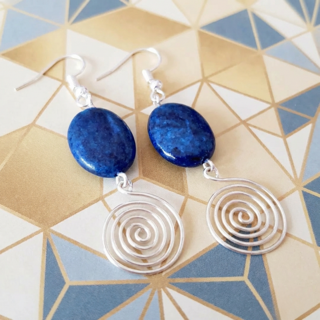Earrings with blue stones and silver spiral designs on a geometric patterned background
