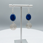 Pair of earrings with blue stones and silver spiral designs on a grey background