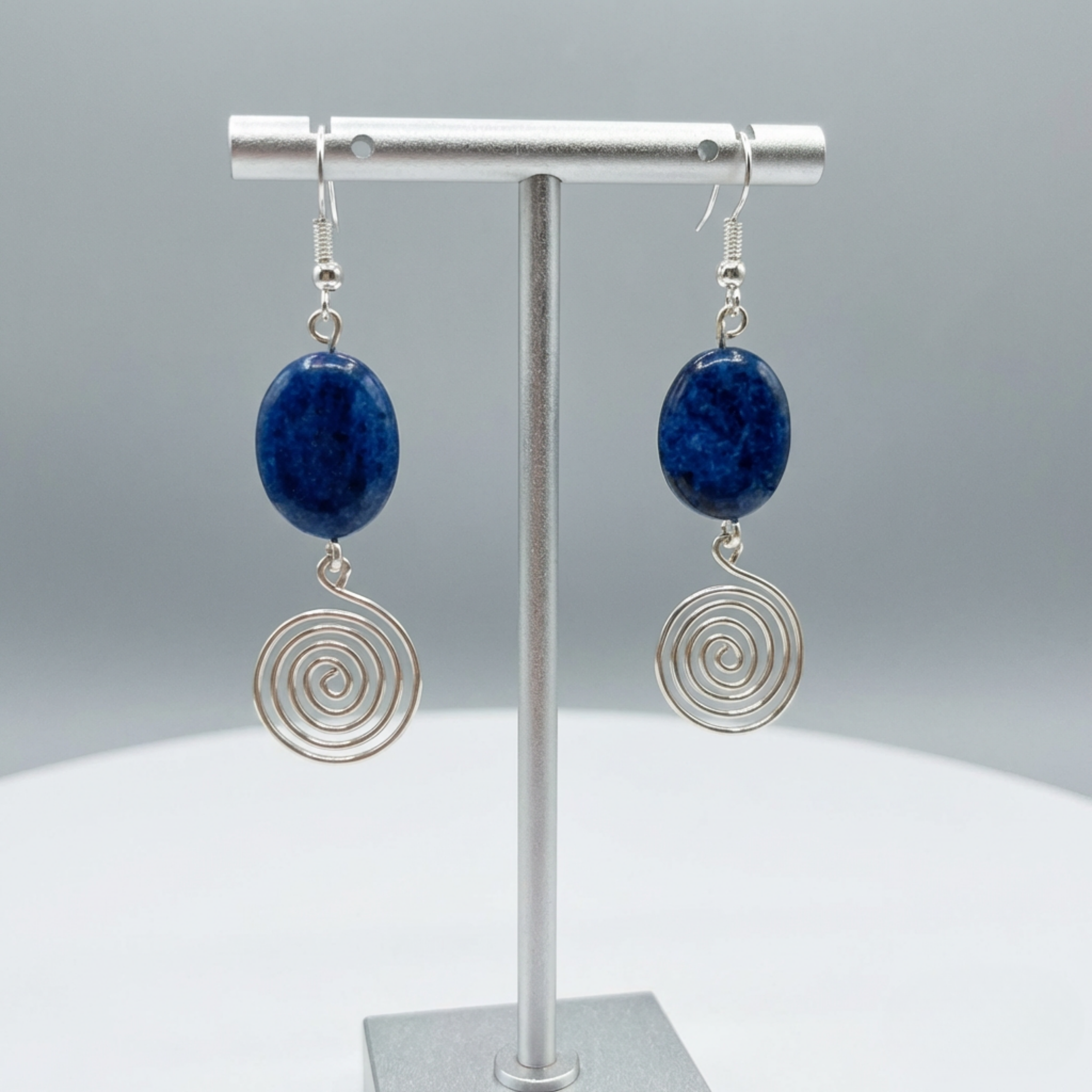 Pair of earrings with blue stones and silver spiral designs on a grey background