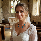 Bride in a wedding dress with a blue beaded necklace with silver spirals in a church setting