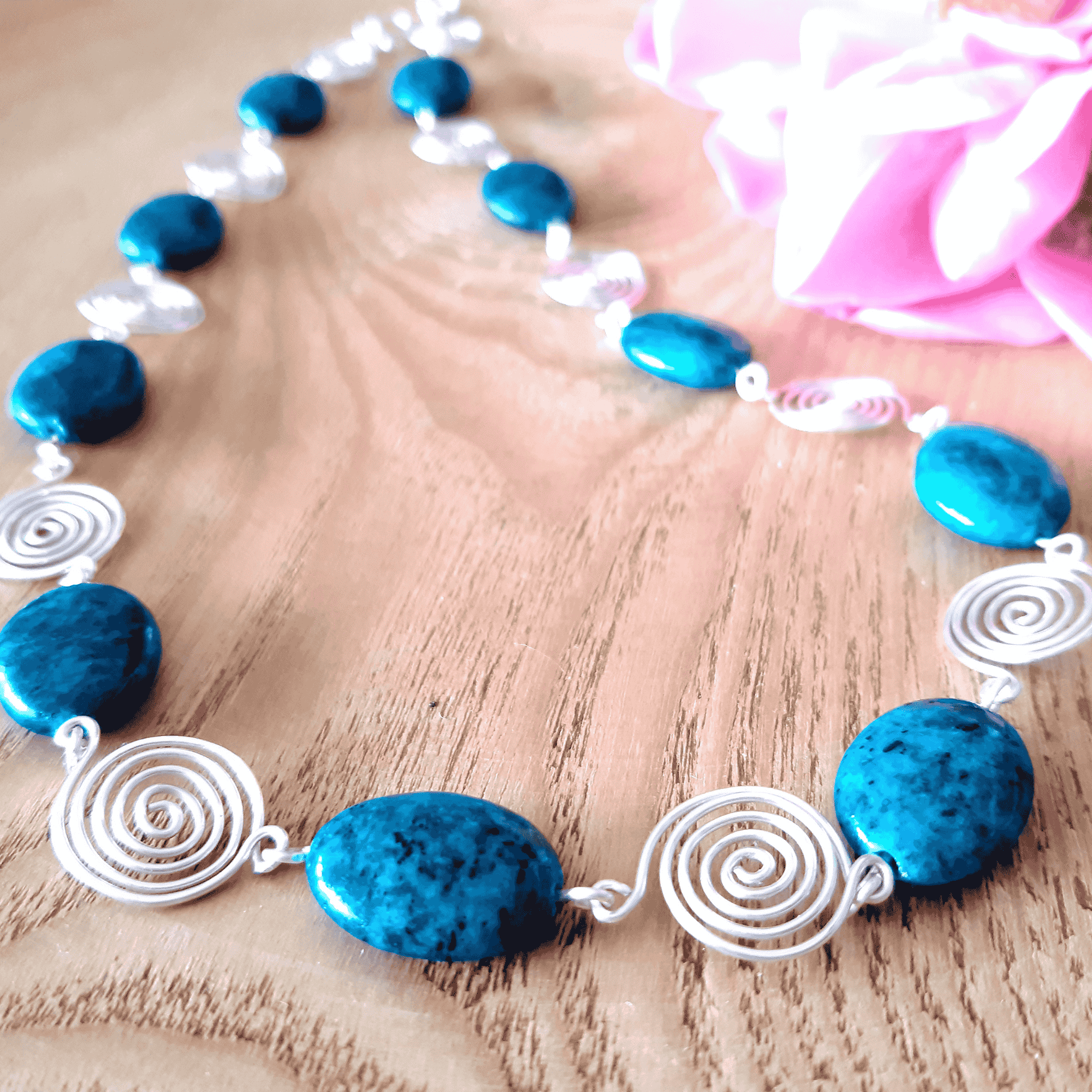 Necklace with blue beads and white spiral designs on a wooden surface