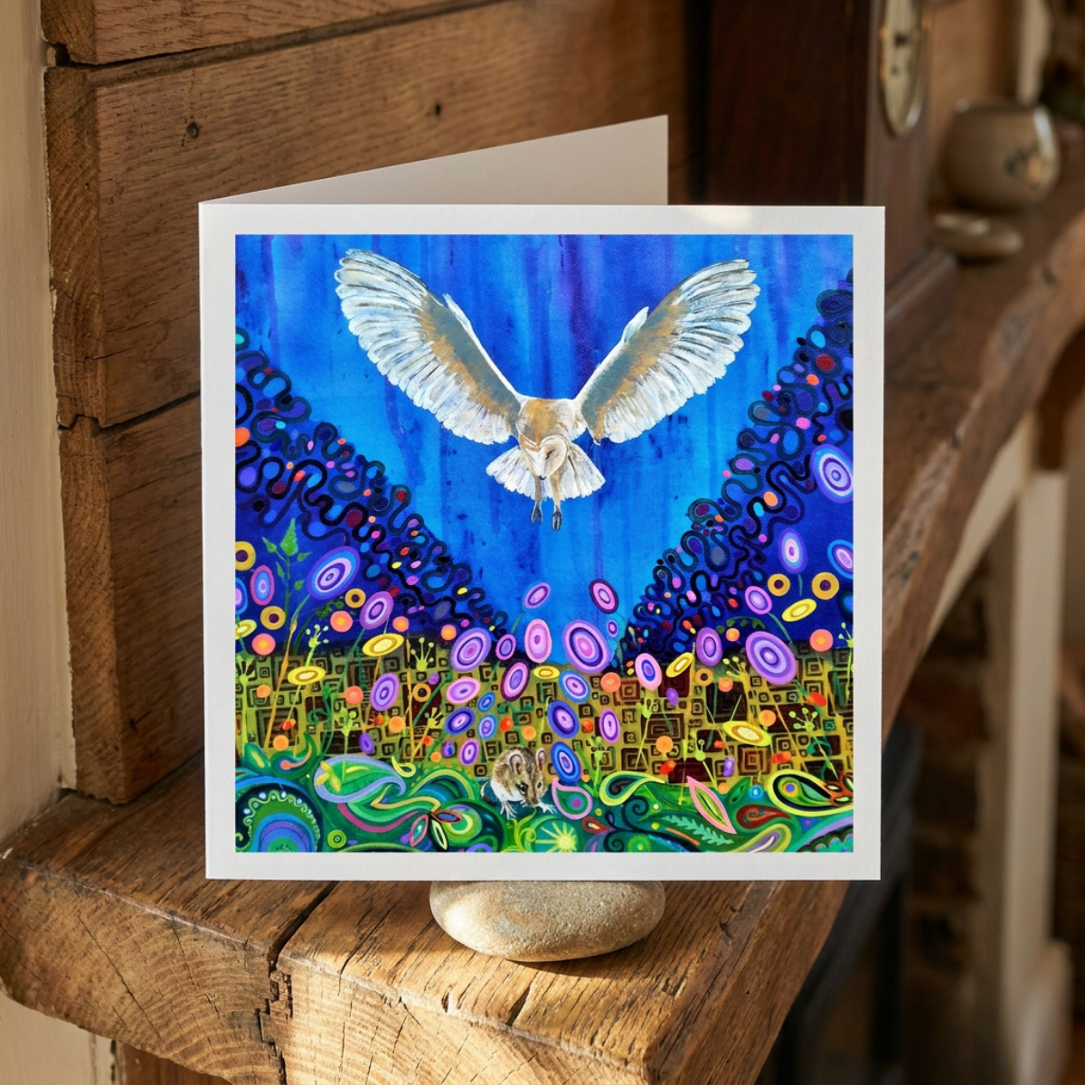Colourful artwork of a bird flying over a vibrant landscape on a wooden surface.