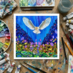 Colourful painting of a barn owl in flight surrounded by abstract floral designs hunting a mouse on a wooden surface with art supplies.