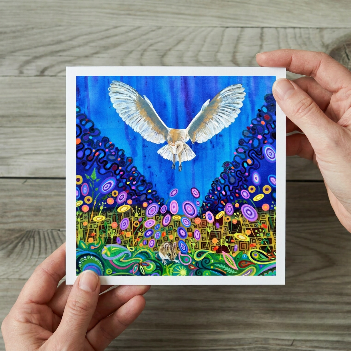 Colourful artwork of a barn owl in flight hunting a mouse held by a person on a wooden surface