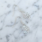 Silver spiral earrings on a marble background