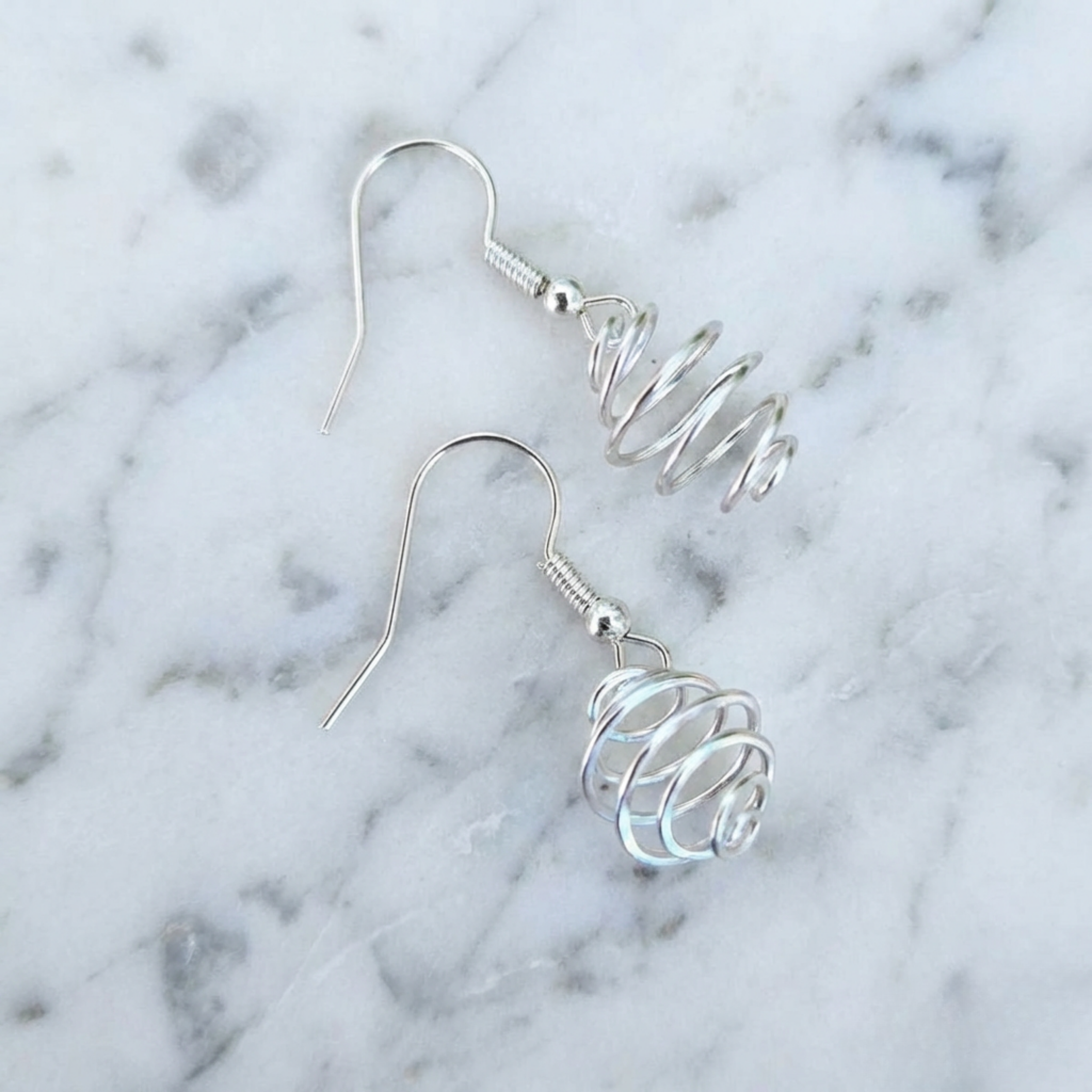 Silver spiral earrings on a marble background