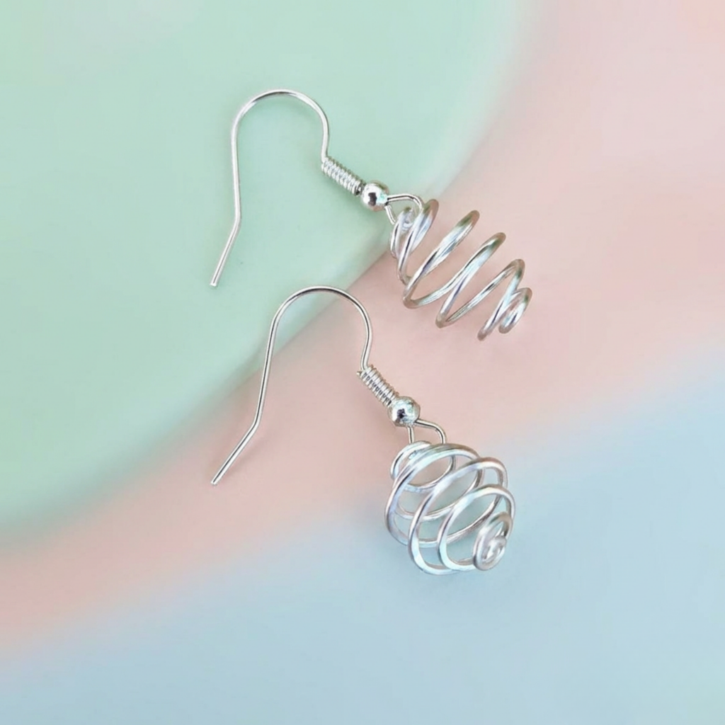 Silver spiral earrings on a pastel gradient background