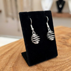 Silver spiral earrings on a black velvet stand with a blurred background