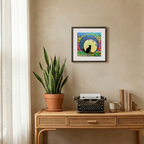 Decorative setup with a potted plant, typewriter, and framed artwork on a beige wall.
