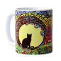 Mug with a colorful design of a black cat silhouette under a moon, on a white background.
