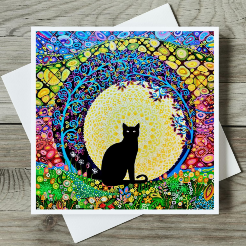Colourful card with a black cat silhouette in a mandala design on a wooden surface.