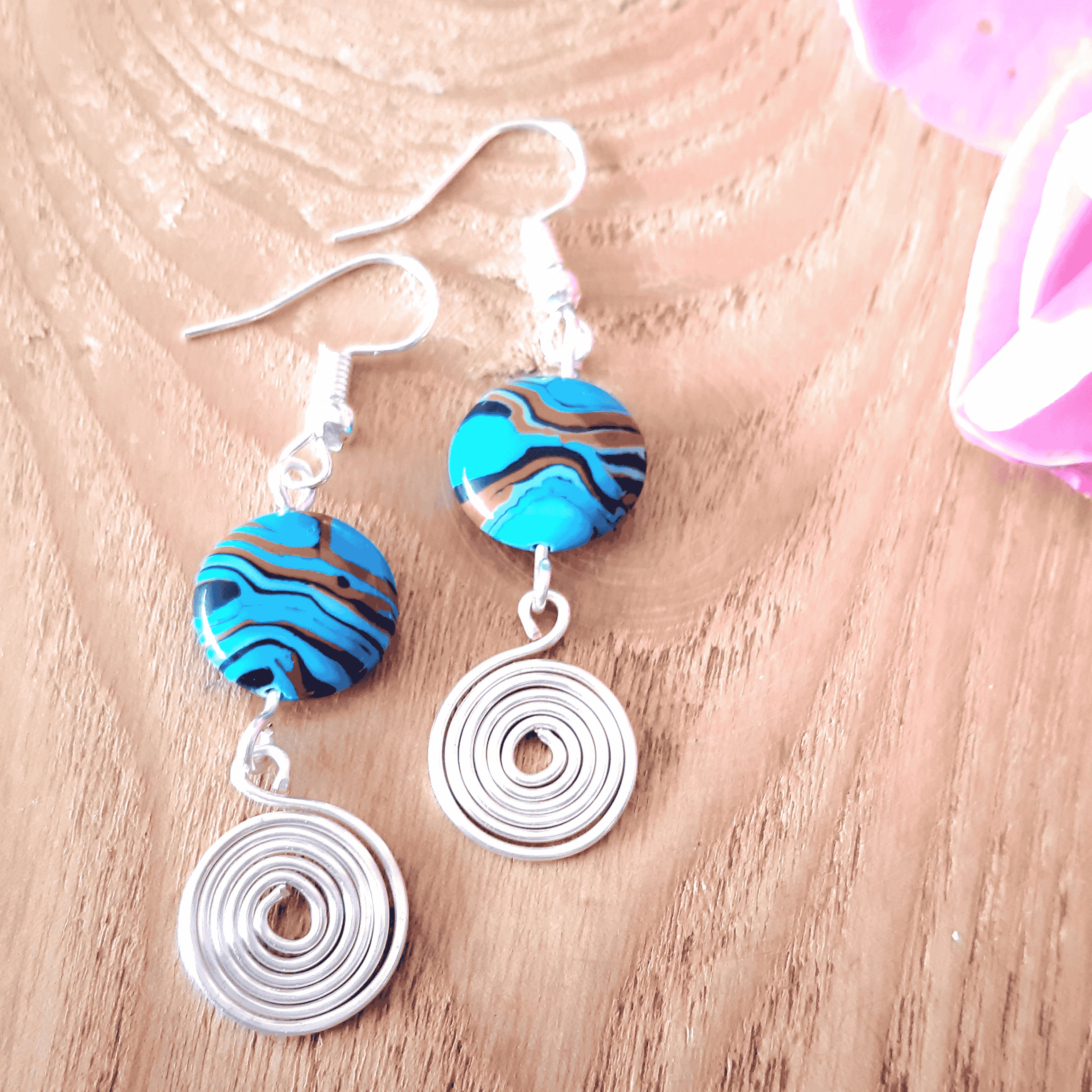 Pair of earrings with blue and brown circular beads on a wooden surface