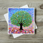 Colourful tree design on a greeting card with a white envelope on a wooden surface