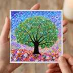 Colourful abstract tree artwork held by hands against a blurred background