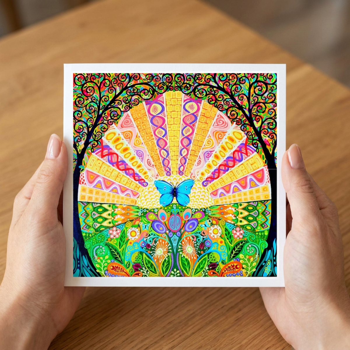 Colourful abstract artwork with a butterfly held by hands on a wooden surface