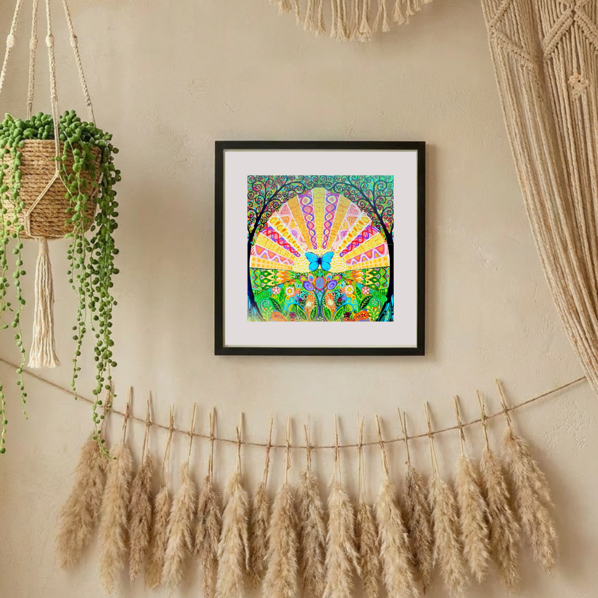 Framed colourful artwork on a wall with decorative elements like pampas grass and macrame.