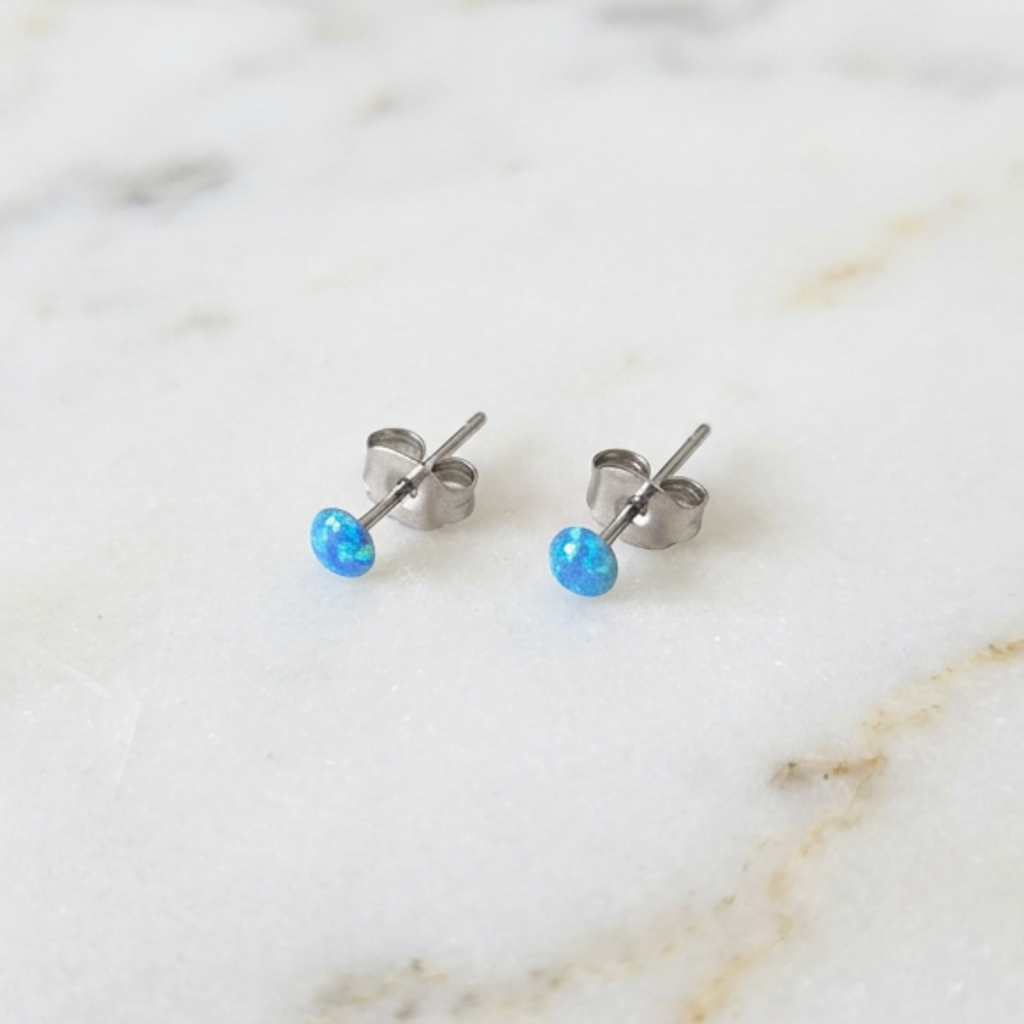 Blue dot studs earrings on a marble surface
