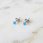 Blue dot studs earrings on a marble surface