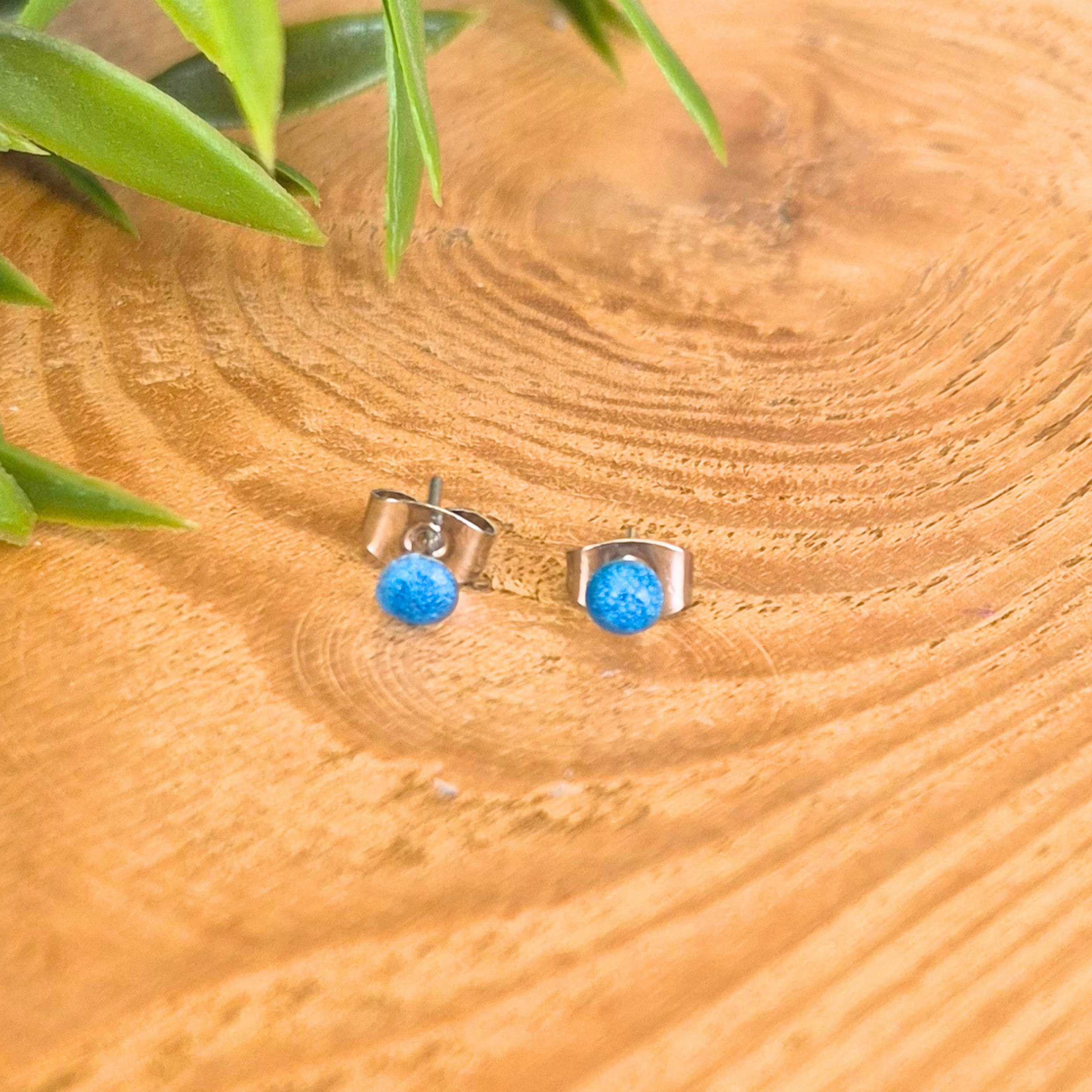 Dot blue stud earrings on a wooden surface