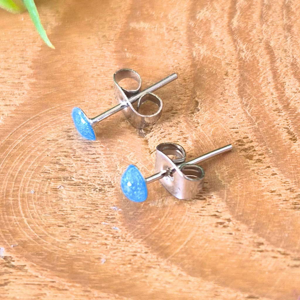 Pair of blue teardrop stud earrings on a wooden surface