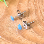 Pair of blue teardrop stud earrings on a wooden surface