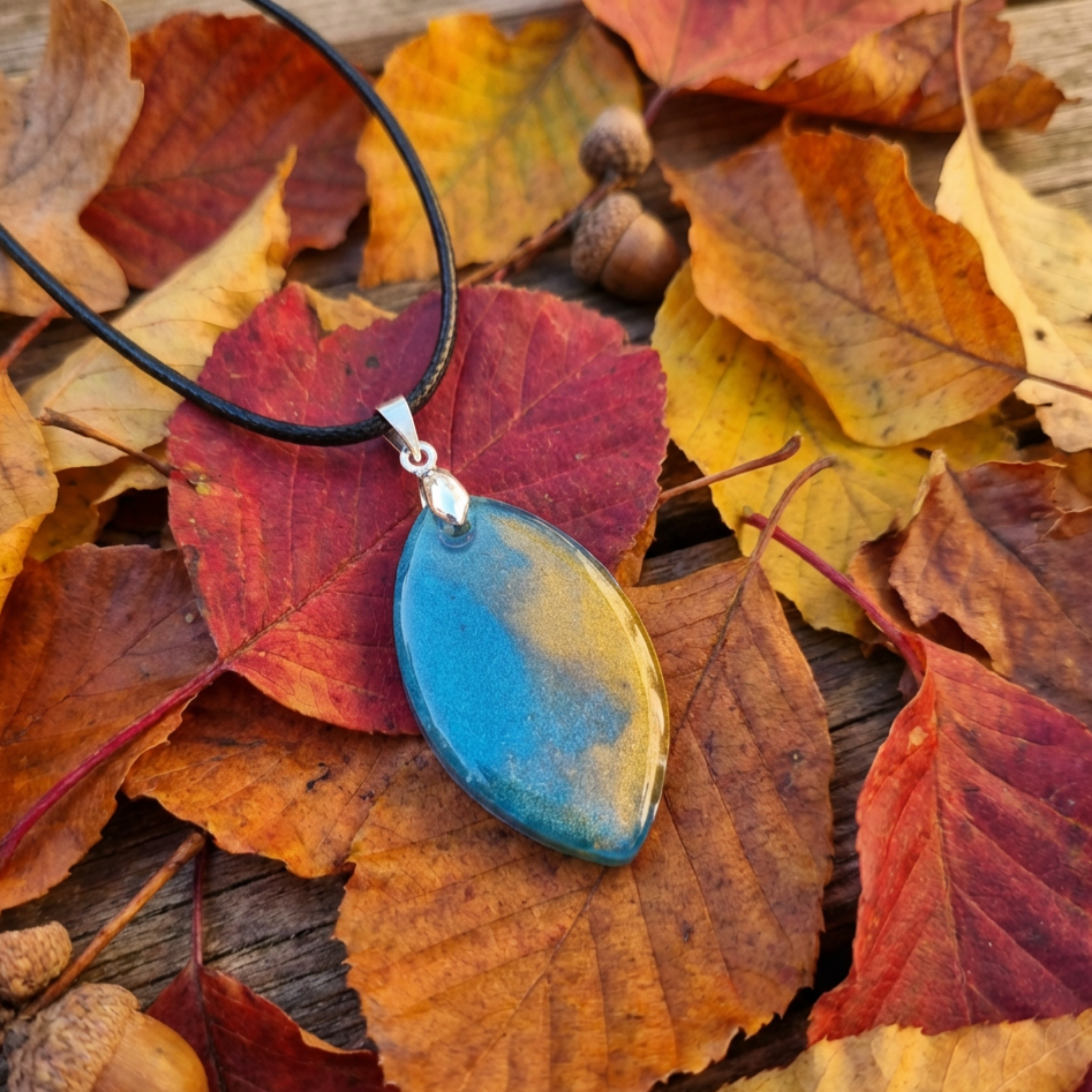 Blue pendant necklace on a bed of autumn leaves