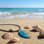 Beach meets sea pendant blue and gold oval on sand surrounded in shells