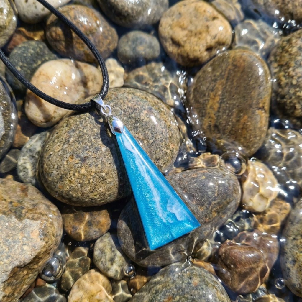 Blue triangle pendant necklace on pebbles with water