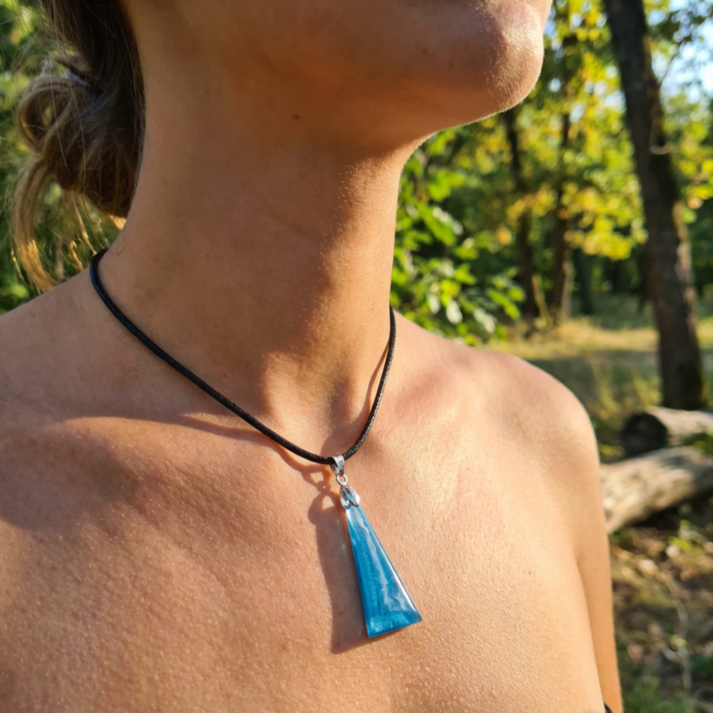Female model wearing a striking blue triangle pendant on a black cord