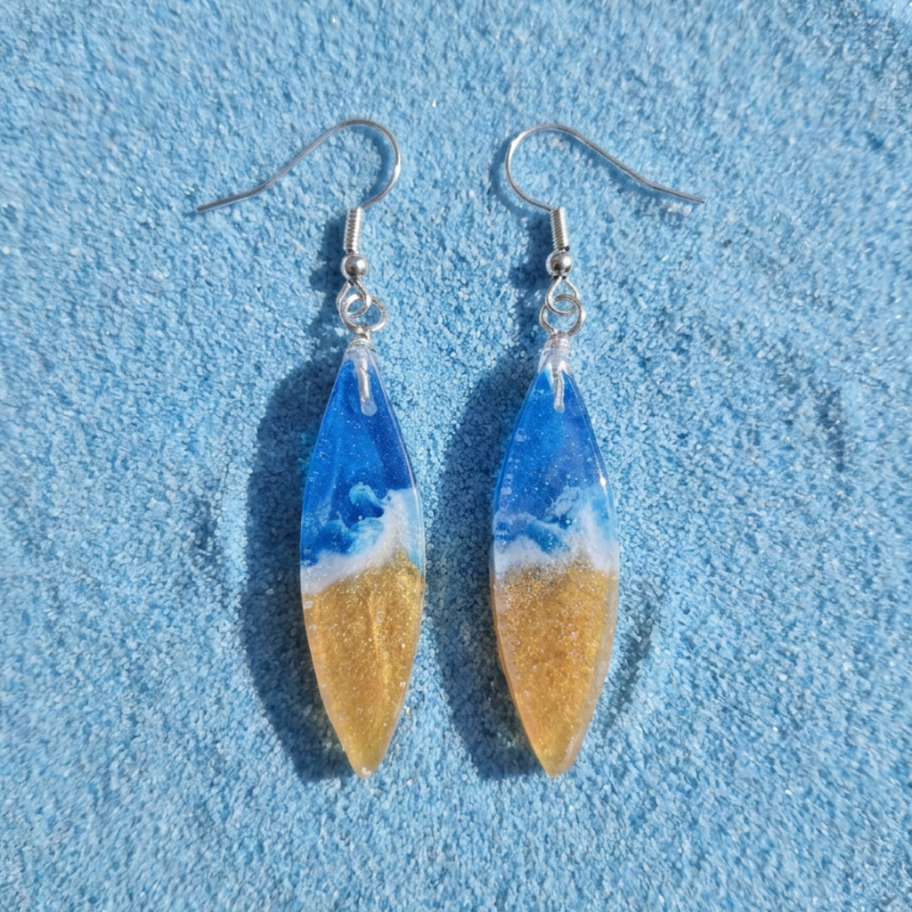 Pair of earrings with blue and gold design on a blue textured background